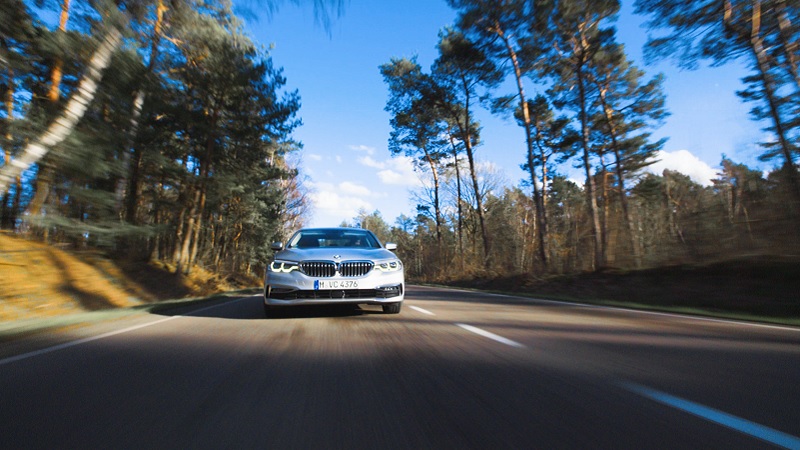 Ein BMW f&auml;hrt auf einer Landstra&szlig;e durch den Wald
