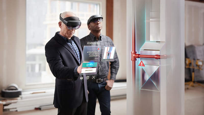 Zwei M&auml;nner betrachten mit einer Hololens ein Hologramm