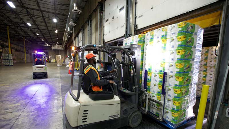 Stapelfahrer in einer Lagerhalle bef&ouml;rdert Paletten von K&uuml;chenpapier