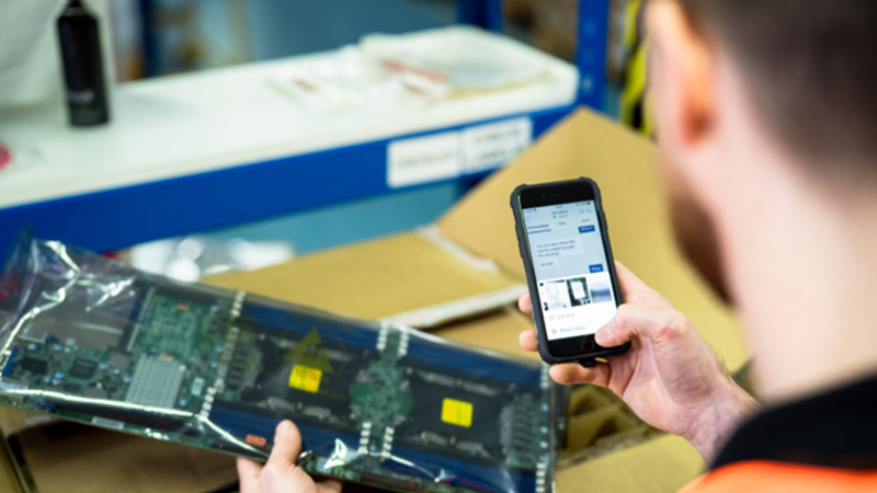 Ein Mann blickt auf ein Smartphone und h&auml;lt eine Verpackung in der Hand