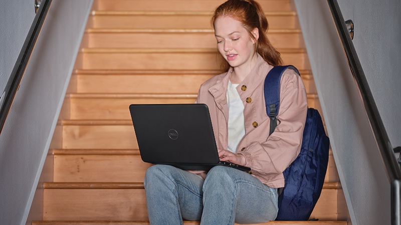 Ein M&auml;dchen sitzt auf einer Treppe, auf ihren Knien h&auml;lt sie einen Laptop