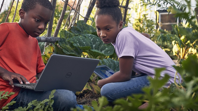Zwei Kinder sitzen in einem Gem&uuml;segarten