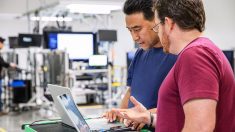 Image of two men speaking together, gesturing a computer screen