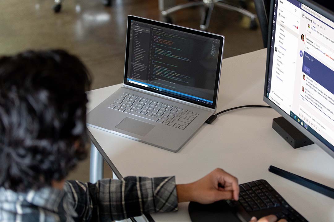 Commercial contextual lifestyle image of adult male at desk workstation on Surface Book 3 in Microsoft Azure and Microsoft Teams