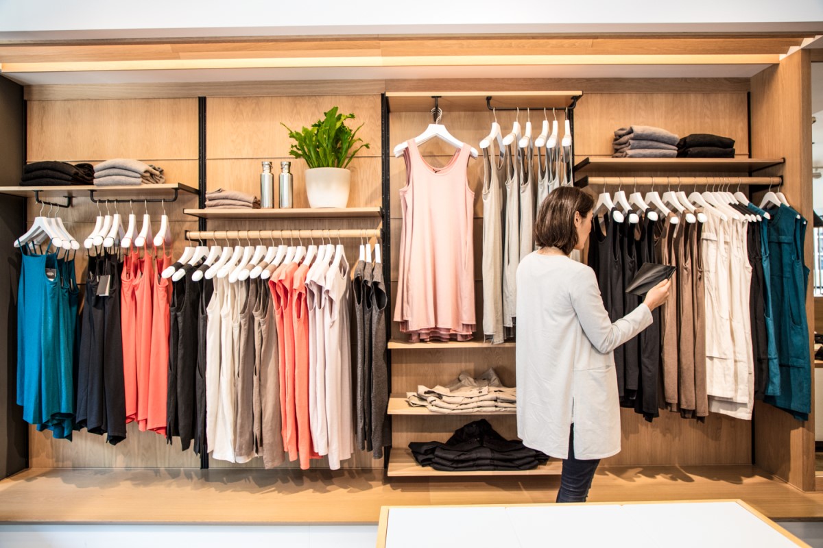 Female store employee using tablet in front of retail clothing display