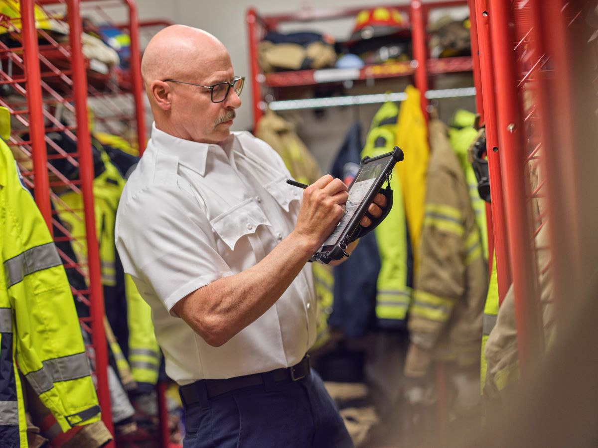 Male firefighter taking equipment inventory using a Surface Go 3 with ruggedized case with Dynamics 365 on the screen
