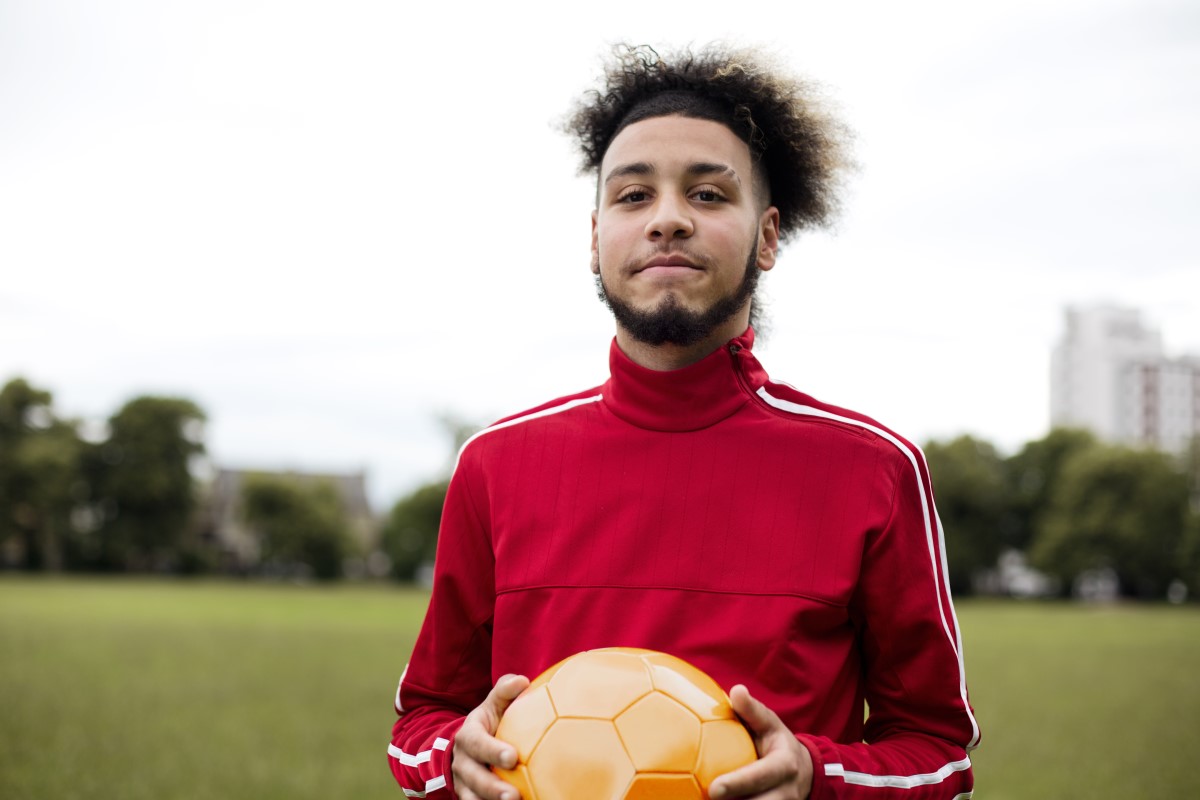 Portrait of a young man holding a ball in a park