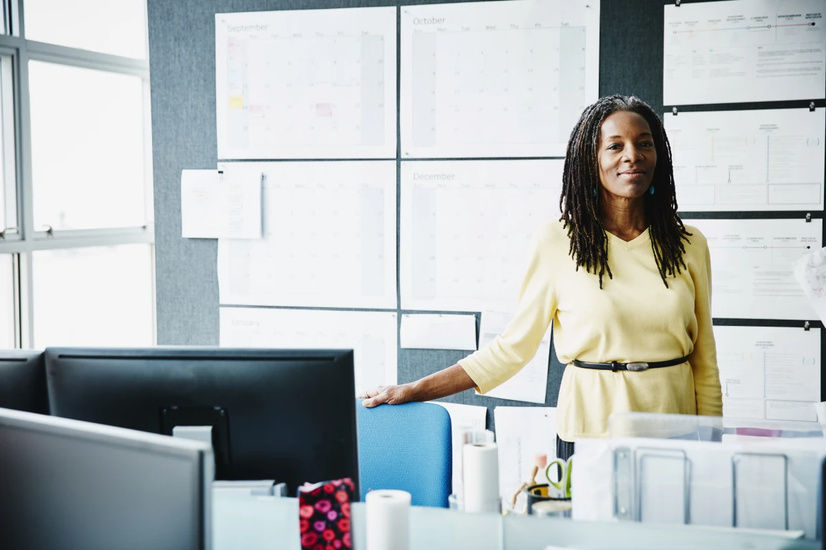 Smiling mature businesswoman standing at workstation in office