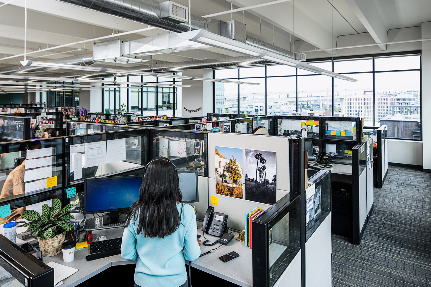 Photo of a female call center agent standing at a cubicle desk in a call center office