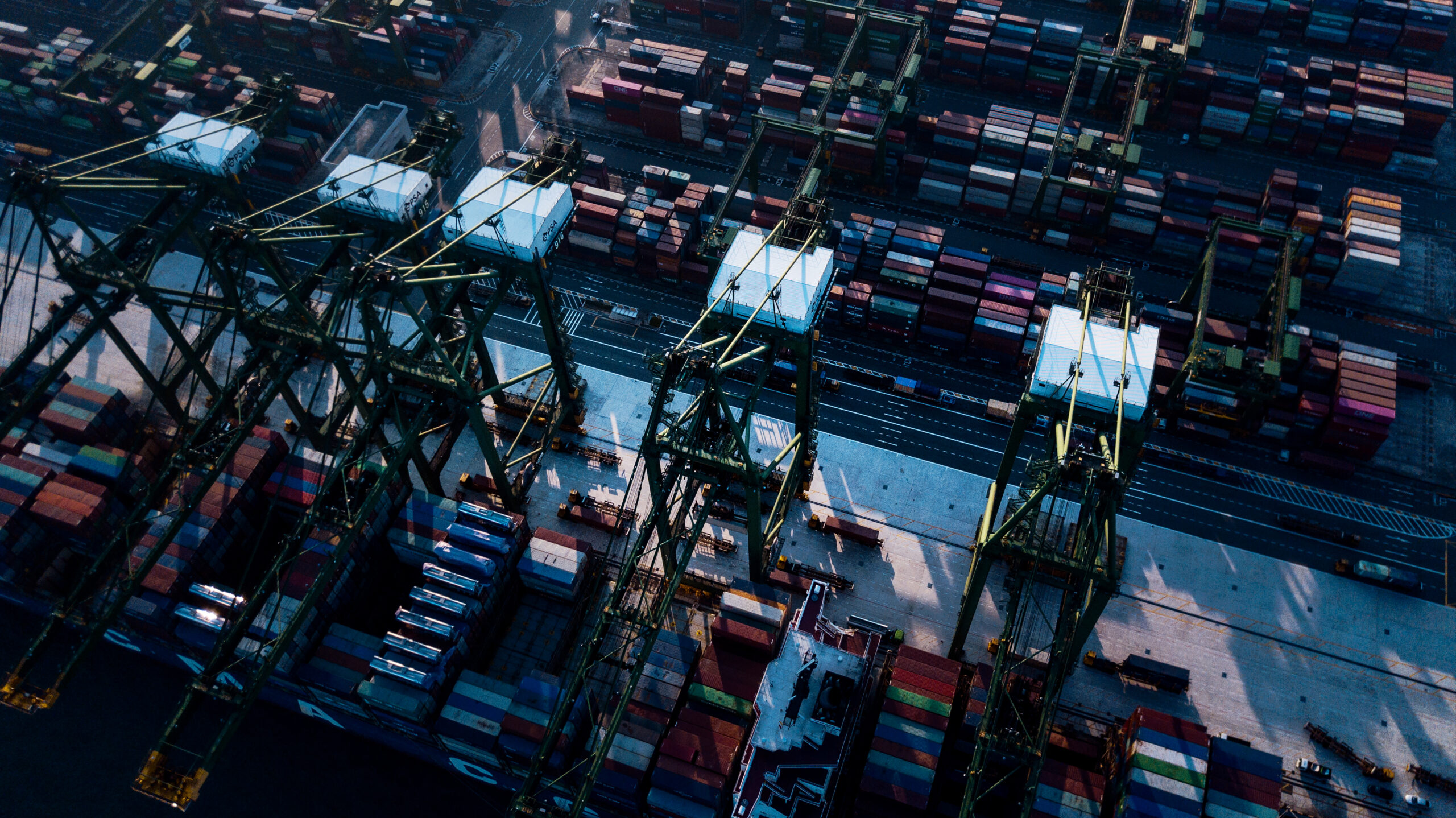 Photo of an aerial view of cranes unloading cargo containers in Singapore shipyard