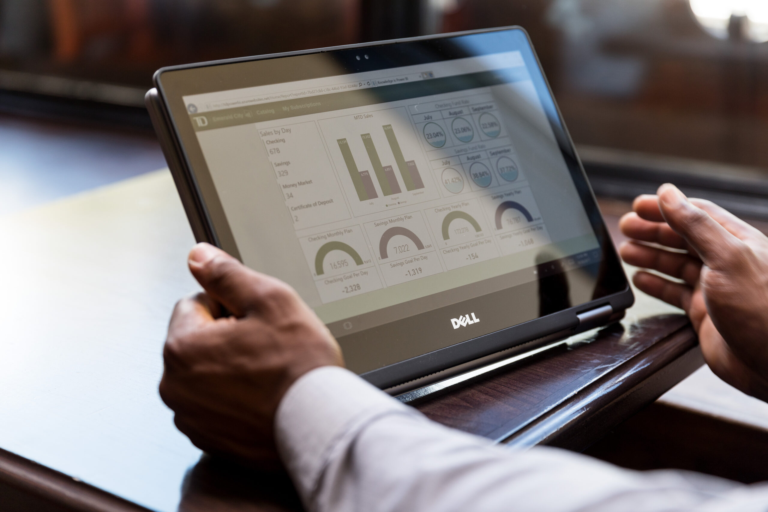 Close up shot of man&lsquo;s hands using Dell convertible laptop as tablet in caf&eacute; restaurant setting. Screen shows charts