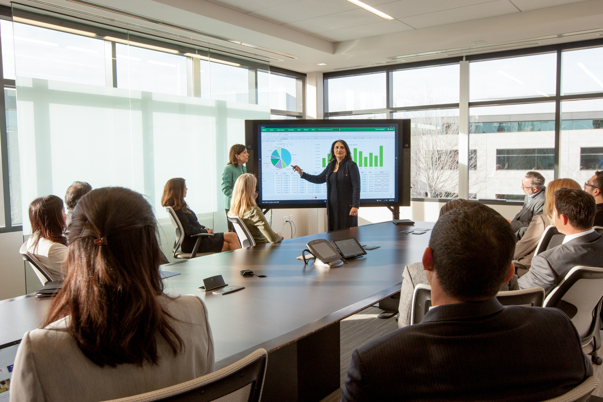 Photo of a group of executives around a conference table, with the CEO pointing to data displayed on a large screen