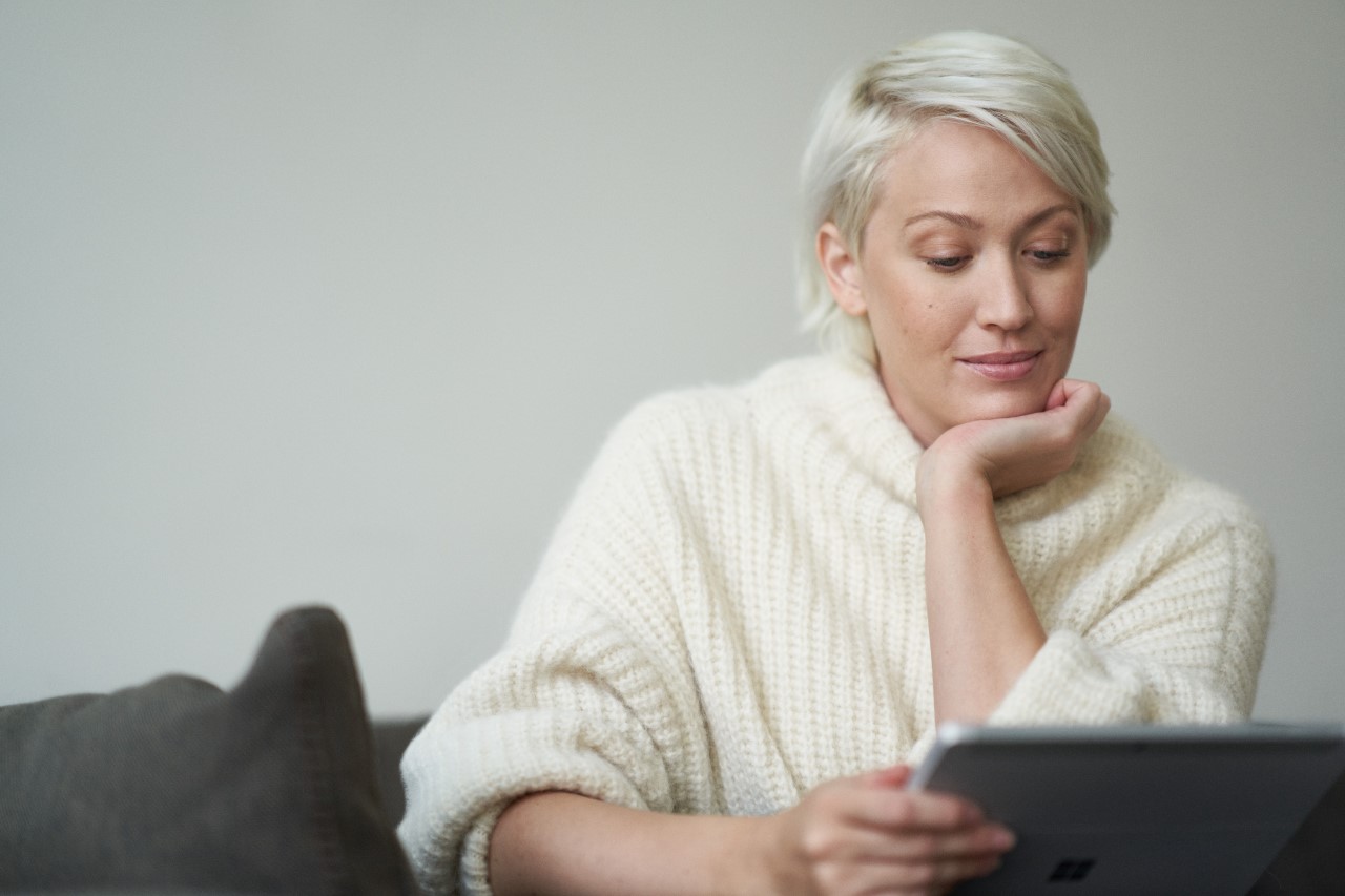 Woman browsing the internet via her tablet while on sitting on a couch