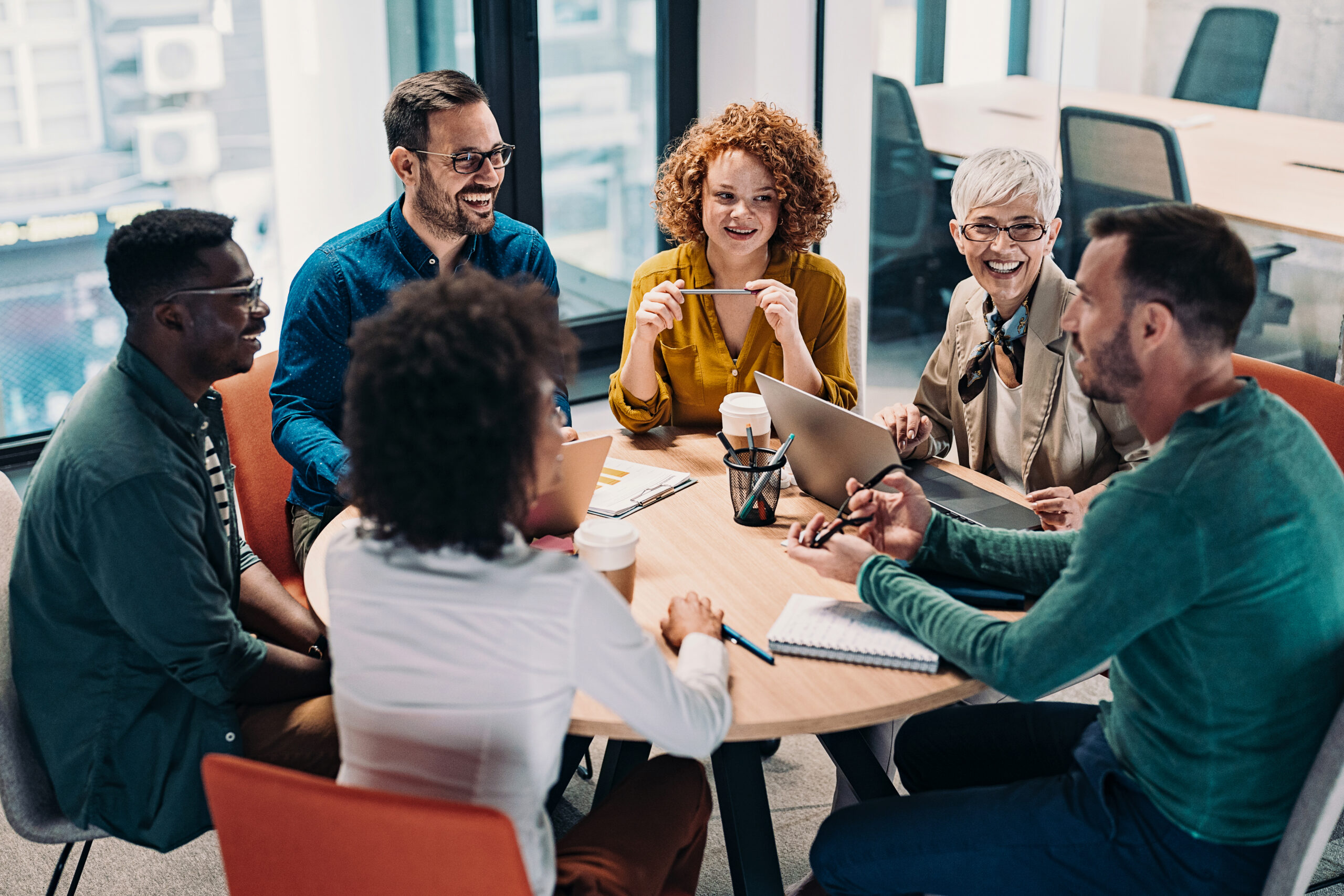Group of business people having a meeting at a round conference table in a creative office
