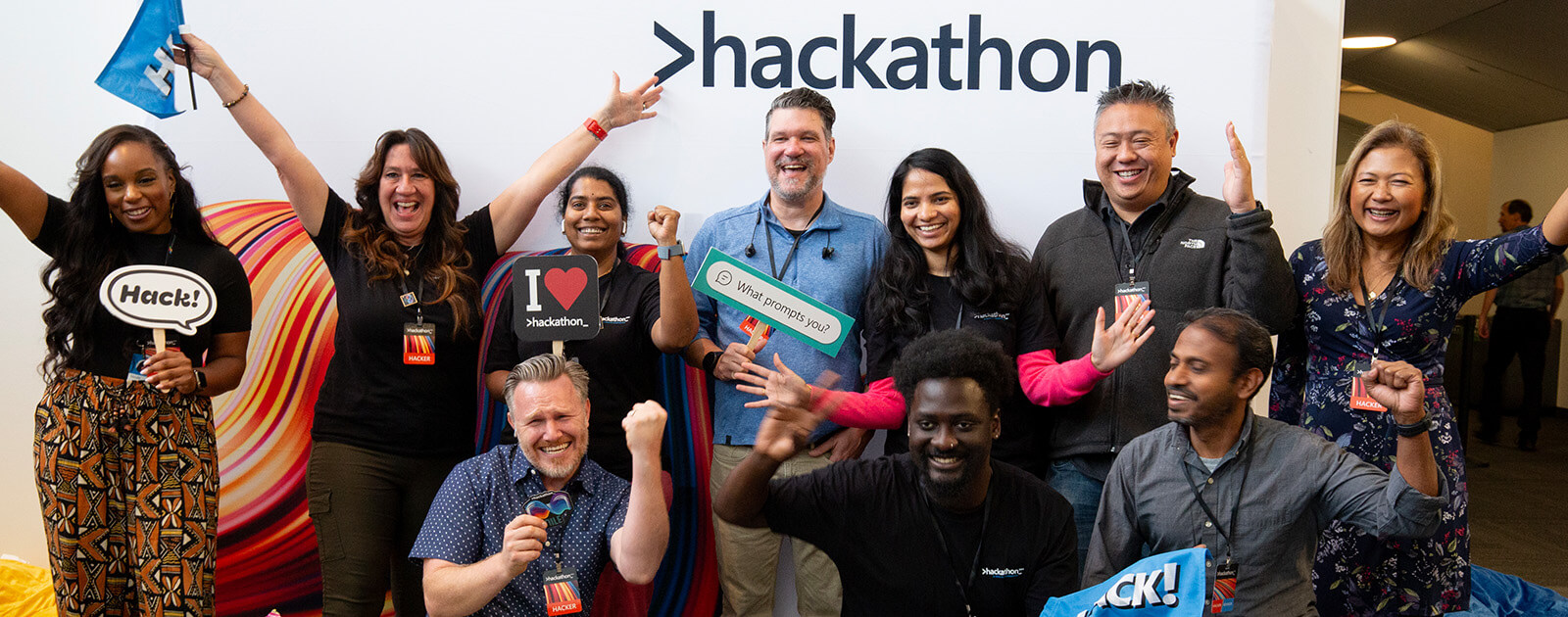 A 2025 Hackathon project team smiling, with their arms raising in celebration