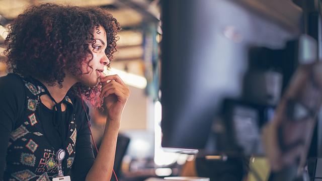 woman deep in thought looking at a monitor