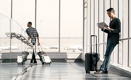 A man waits in an airport holding an electronic device