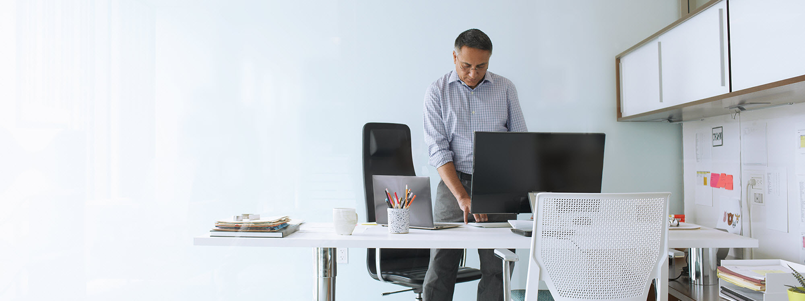 Image of a man standing at his desk and working on his desktop computer