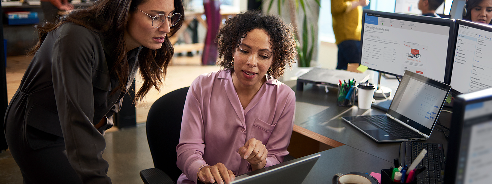 Image of two tech workers collaborating over a laptop