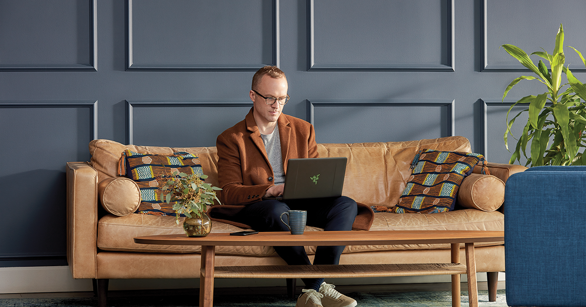 Image of a man working with a laptop PC on a couch
