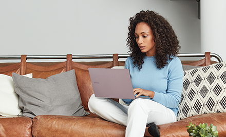 A woman sitting on a couch using her PC laptop