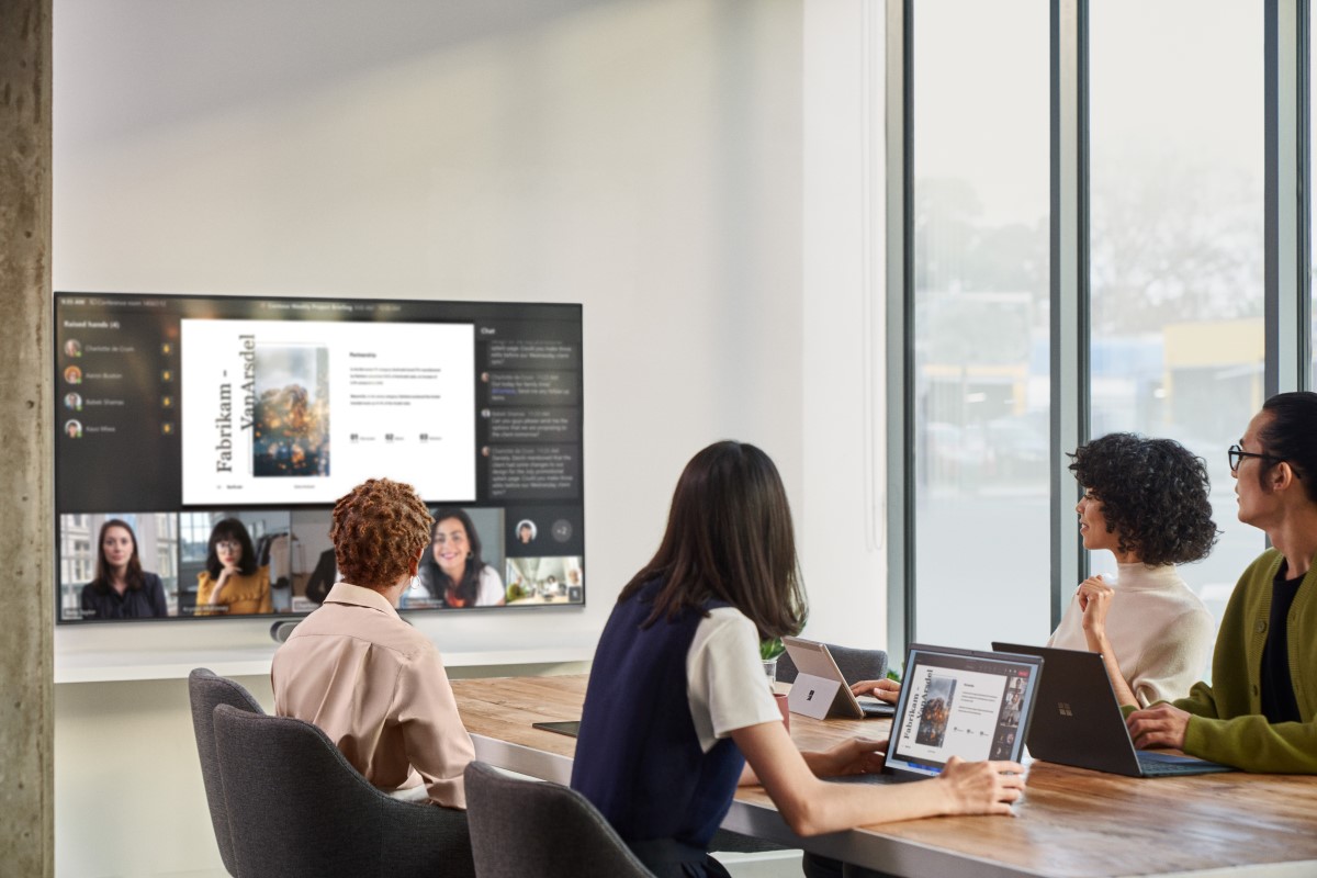Remote attendees participating in a Microsoft Teams Room (MTR) meeting while people in a conference room are viewing PowerPoint content on the front of room (FoR) screen displaying remote participants in Front Row