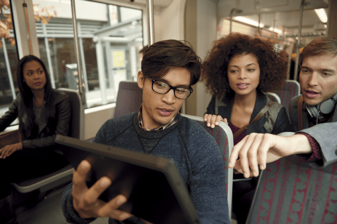 Four people looking at a tablet together in an office