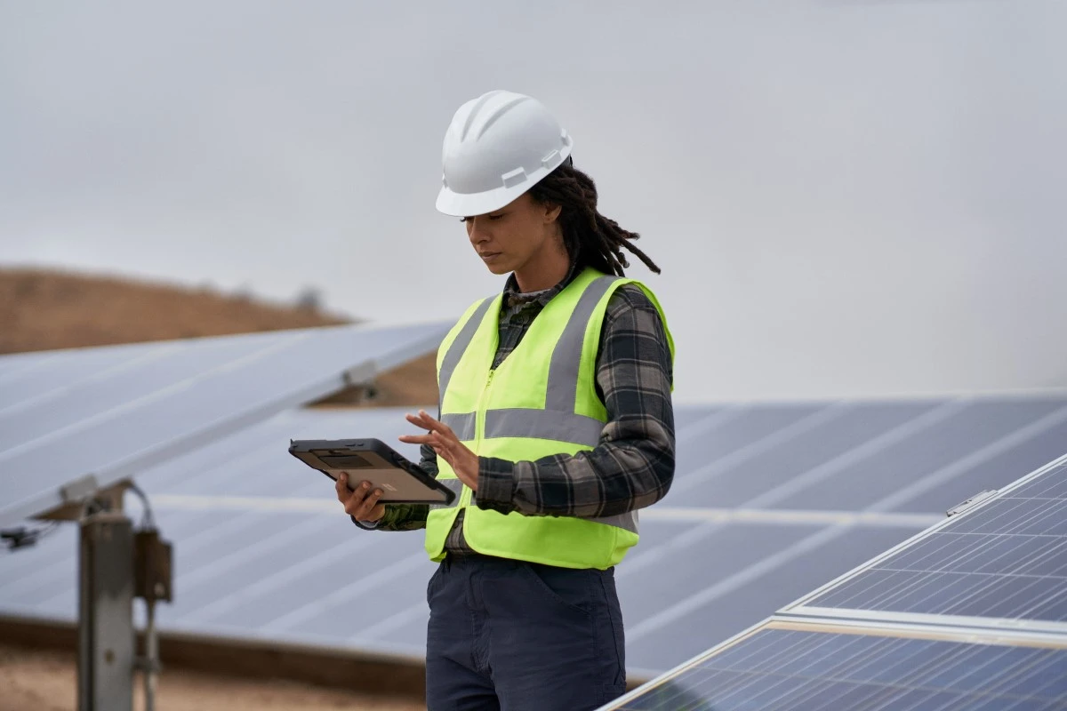Field engineer inspects solar panels on a wind farm using remote assist with a Surface tablet