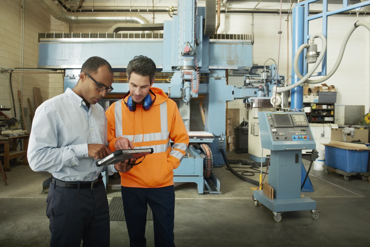Manufacturing engineers interacting, tablet in hand