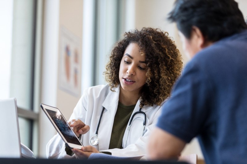 A physician showing something on a tablet to a person