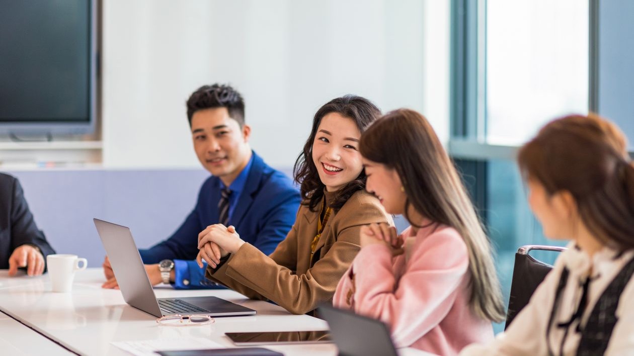 A group of smiling businesspeople collaborate in a meeting room