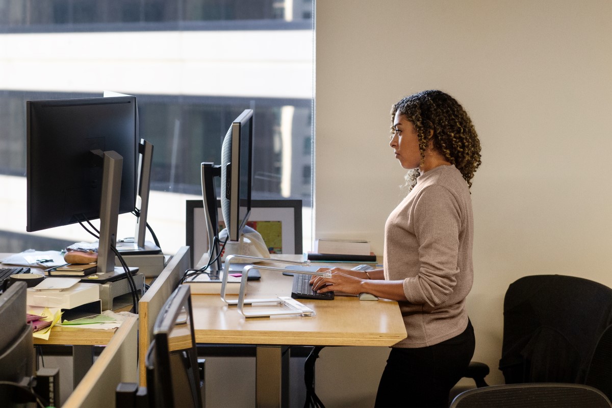 Real people, real offices. Black female developer doing focused work at a standing desk in enterprise workspace. Focused work. Women who code, women developers, women engineers, code, develop, Black developer, engineer, Visual Studio, Azure