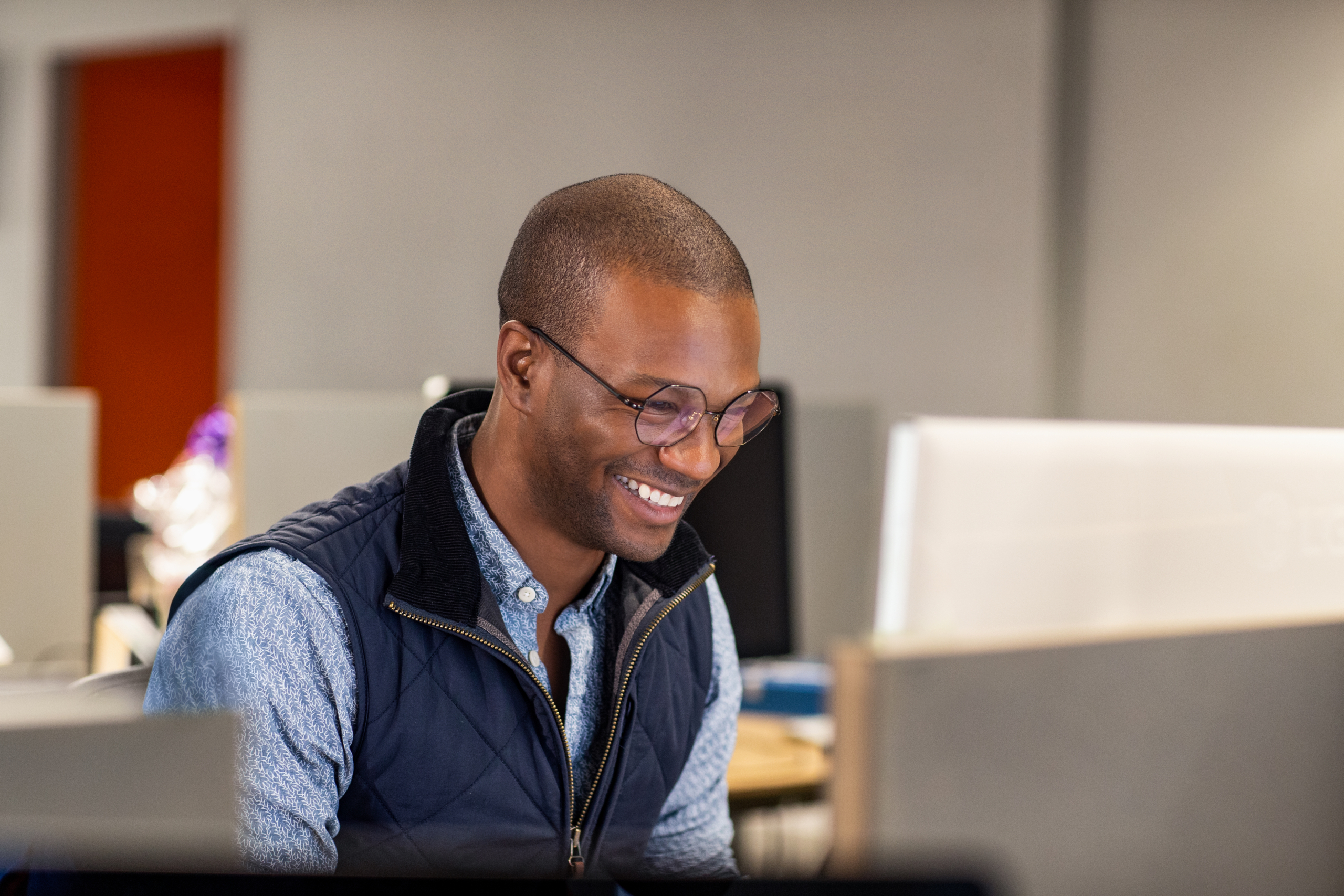 Real people, real offices. Black male developer smiling while at work in an Enterprise office workspace. Focused work. Code, develop, black developer, engineer, Visual Studio, Azure