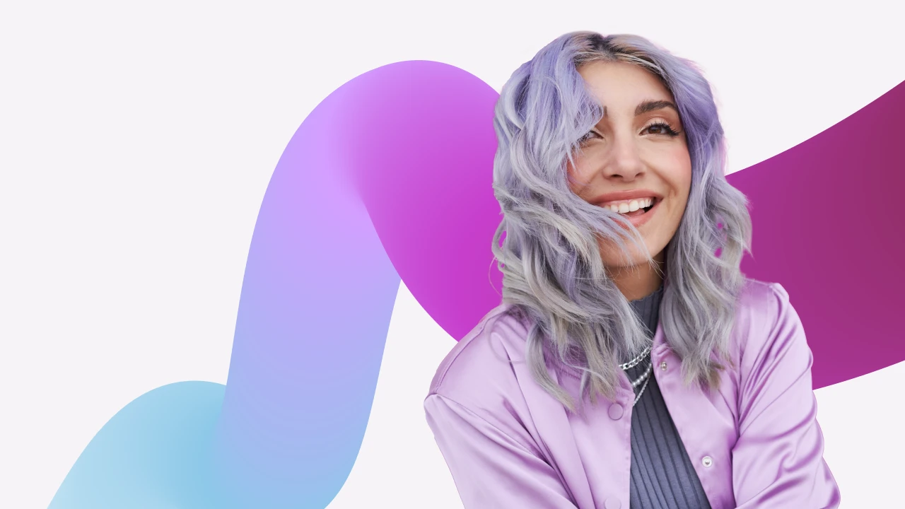 Portrait of a woman smiling with hair in her face in front of a decorative background