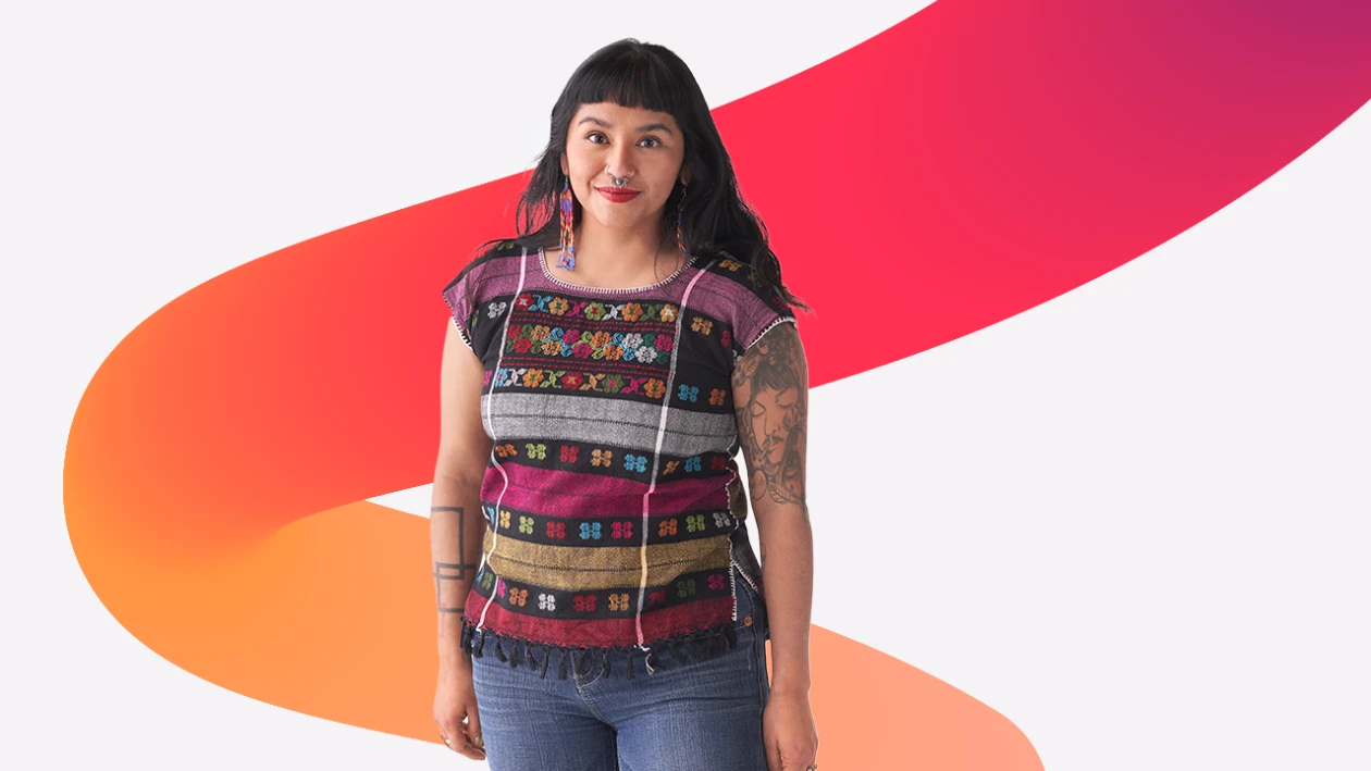 A person with tattoos on their arms, wearing a colorful shirt looking at the camera. A red and orange gradient squiggle design is in the background