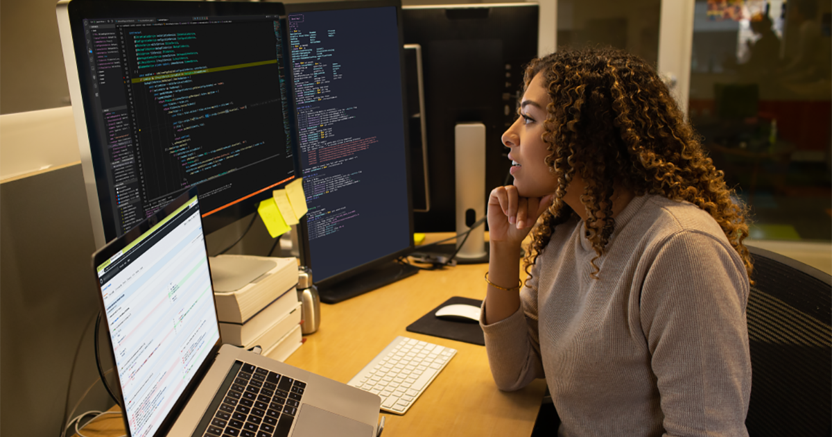 Real people, real offices. Female developer coding at her desk