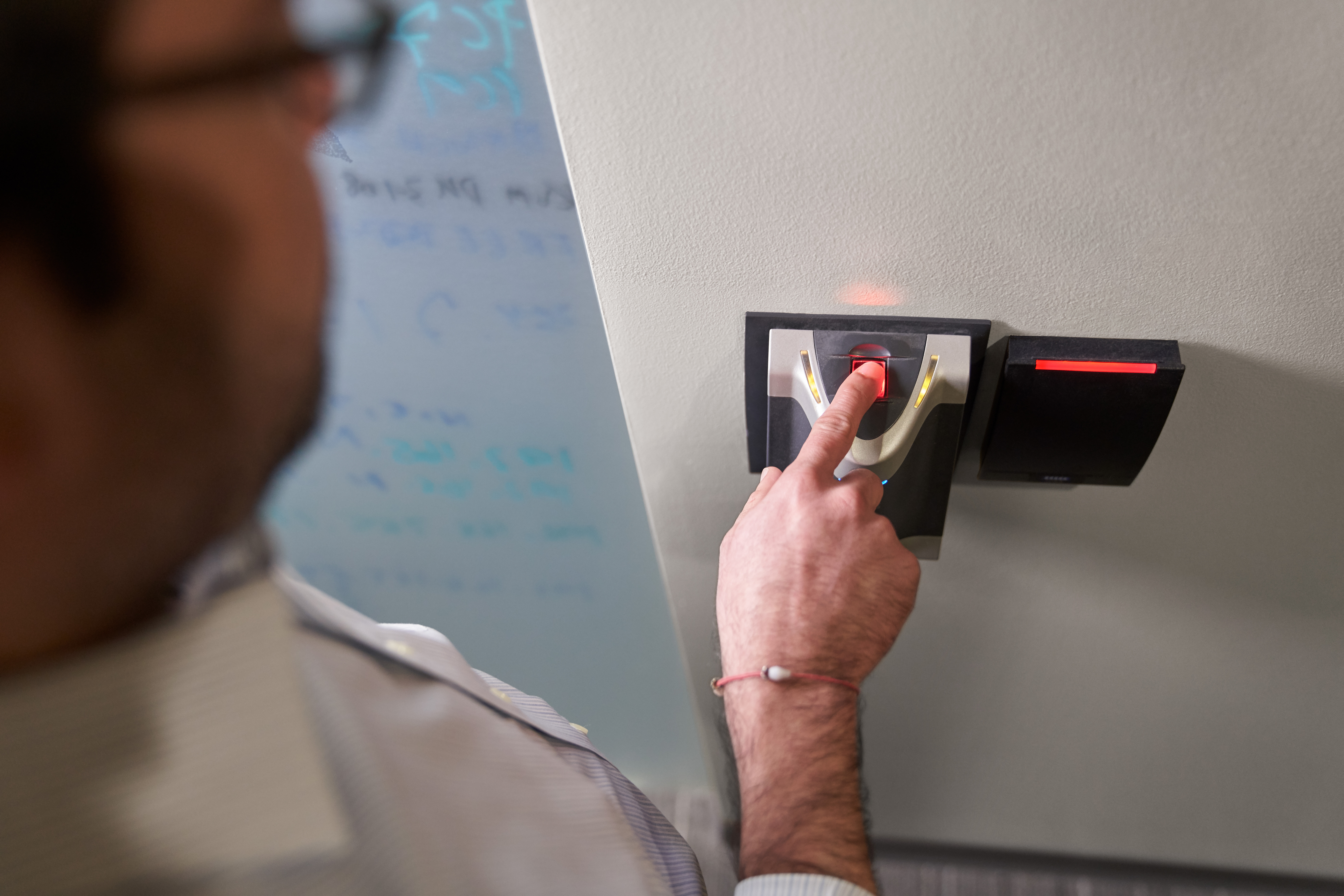 Man scanning his finger in a biometric fingerprint reader which will provide him access to a room