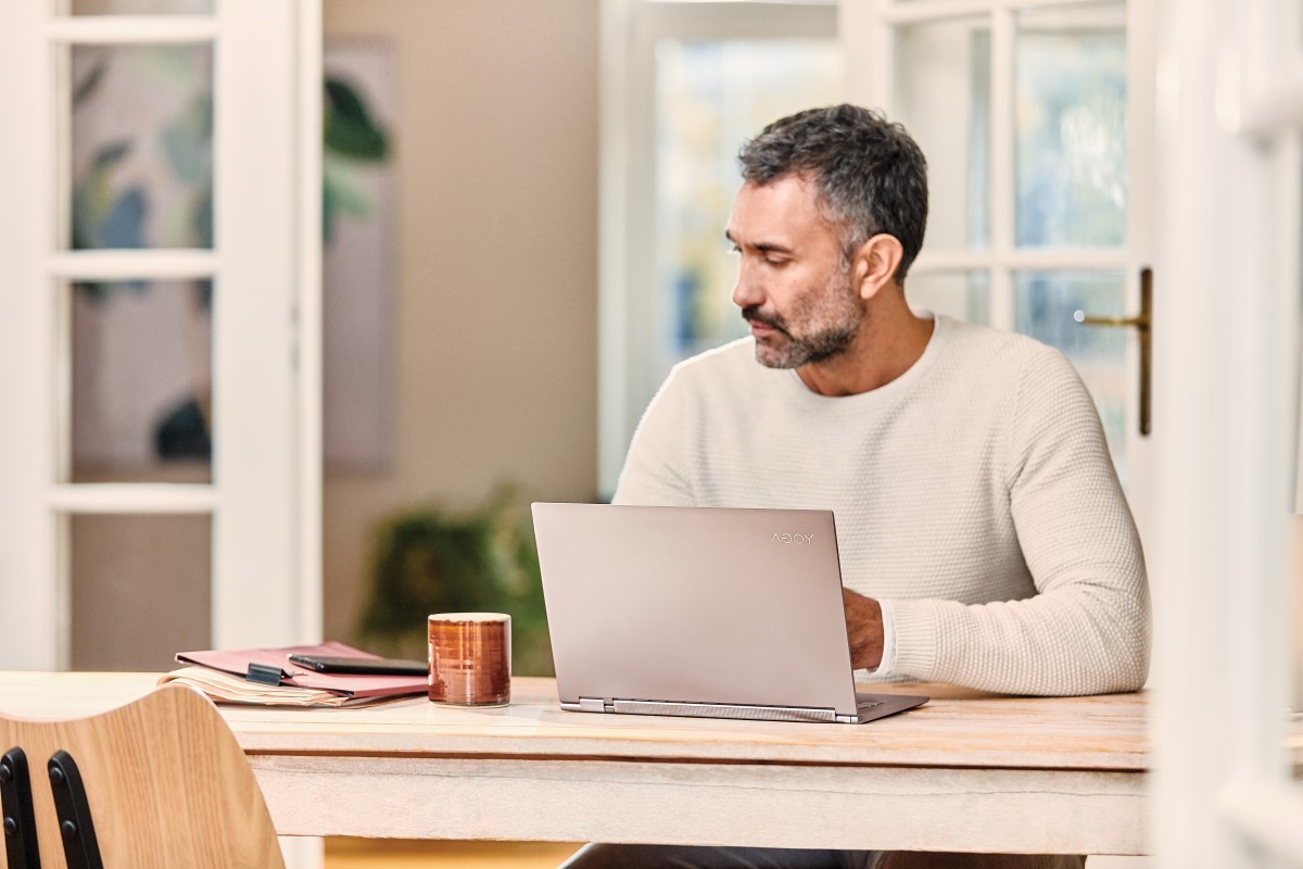 Mobile professional looking at his phone working from home on Lenovo Yoga C930 laptop