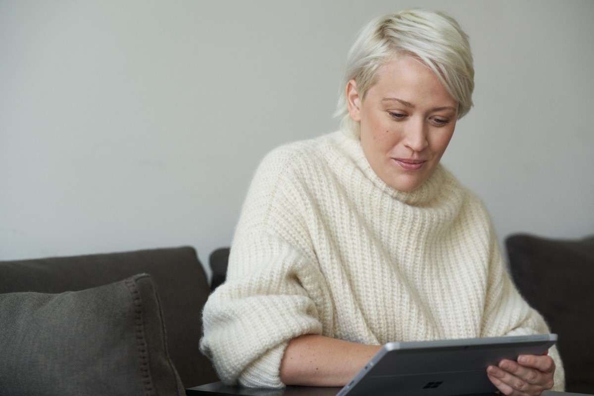 Woman using a credit card to place a secure online order via her tablet while sitting on her couch at home