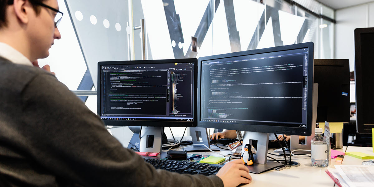 IT professional looking at computer screens that display lines of code