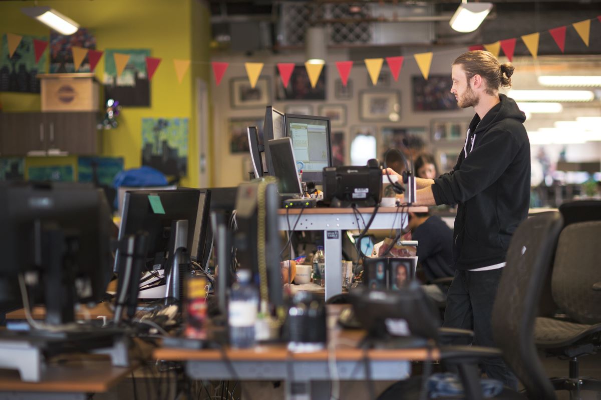 A man standing in their workstation with multiple computer screens
