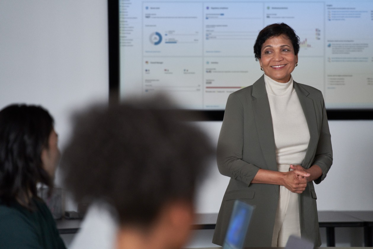 A woman in a suit standing in front of a large screen