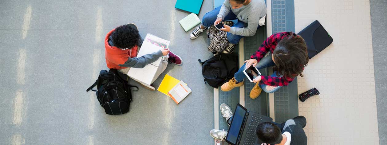Una vista aerea di un gruppo di studenti che studiano con laptop, tablet e smartphone