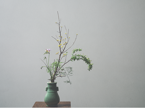 緑色の花瓶に生けられた花。