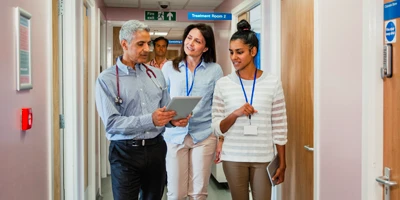 Equipe de 3 médicos andando pelo hospital com o tablet na mão