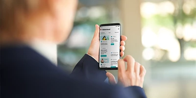 Pessoa olhando para o celular com tela de app aberta